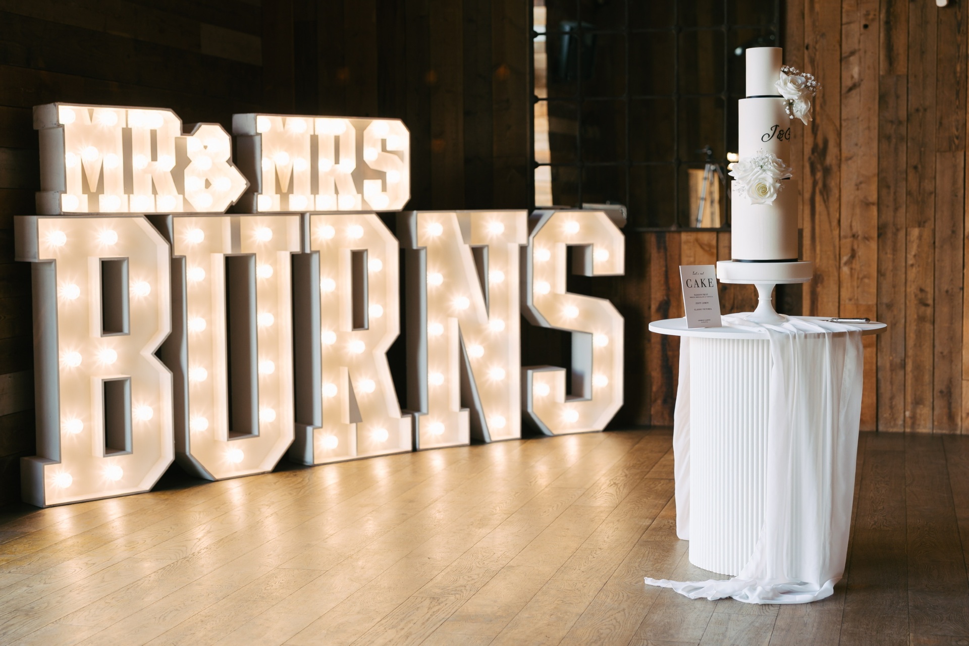 Giant white light up MR & MRS BURNS marquee letters at a rustic Yorkshire barn wedding