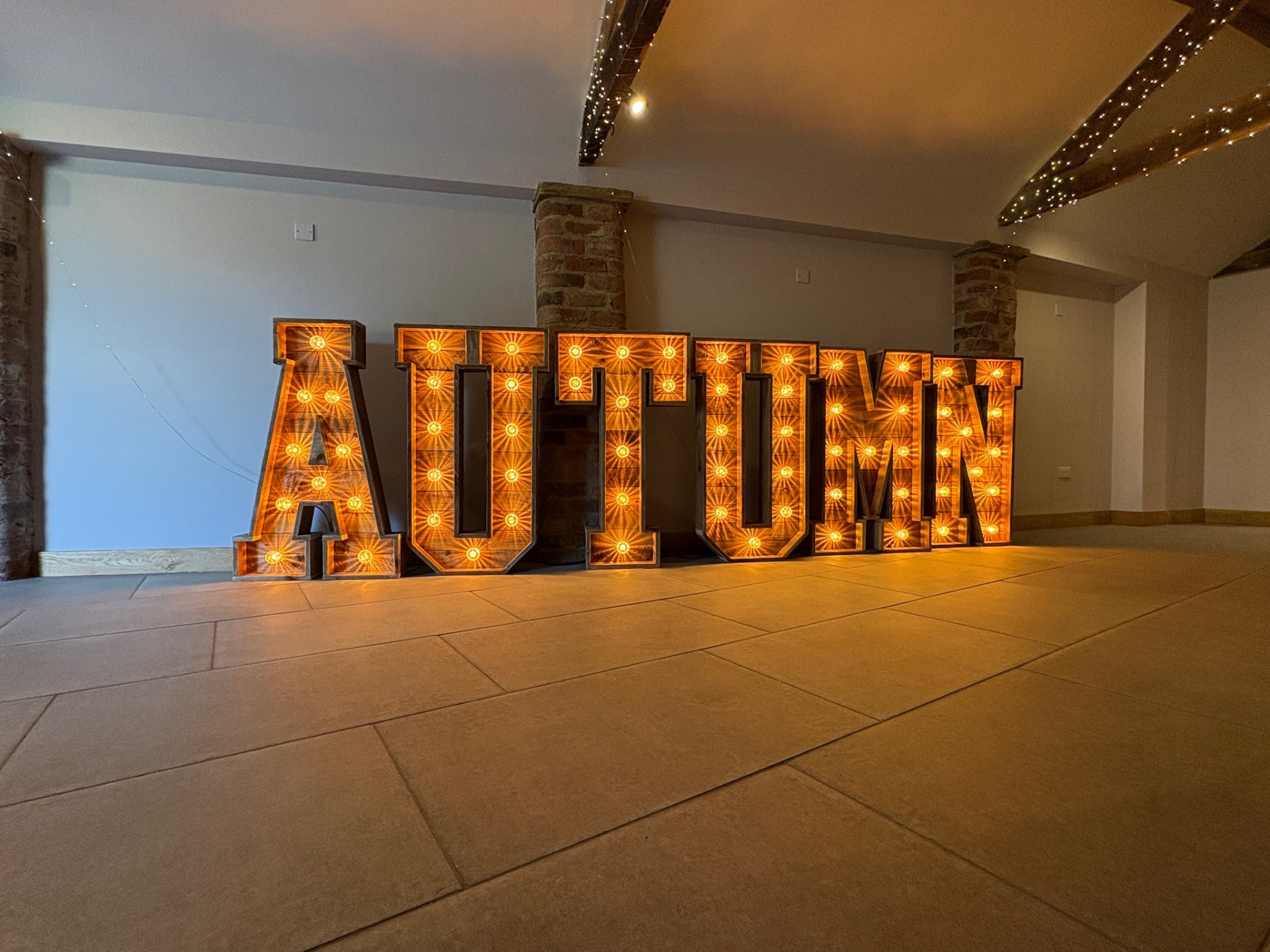 Giant rustic wooden light up AUTUMN marquee letters with warm edison bulbs in a Yorkshire barn
