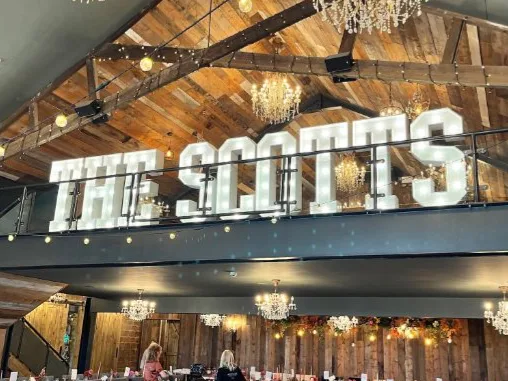 White light up letters spelling THE SCOTTS in a barn venue
