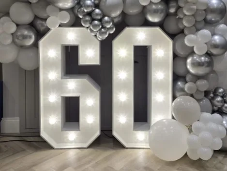 White light up number 60 with a silver balloon garland