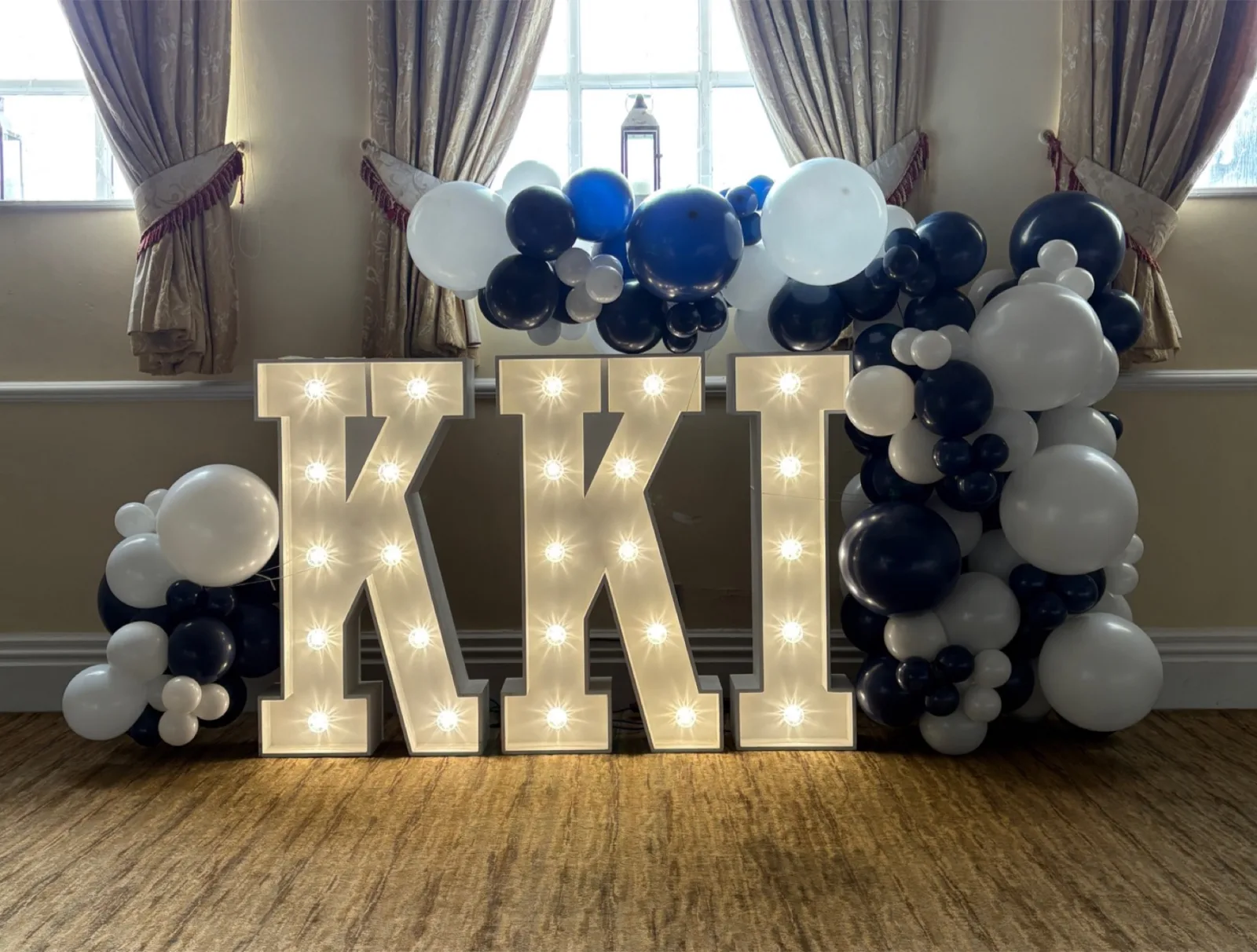 White light up letters with a blue and white balloon garland