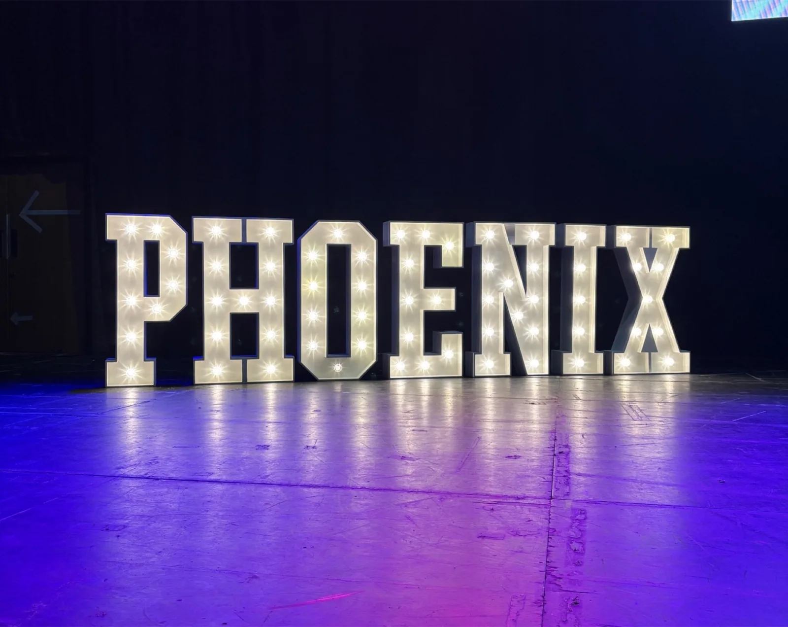 White light up letters spelling PHOENIX under purple lighting